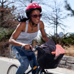 A woman rides a bike with a full basket and a smile
