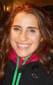 A woman in a coat smiles at the camera